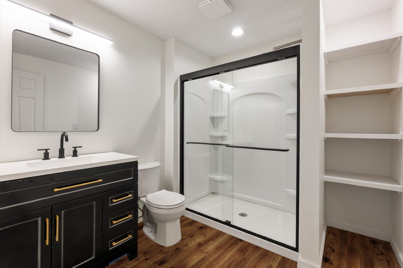 Remodeled bathroom with black vanity and glass shower