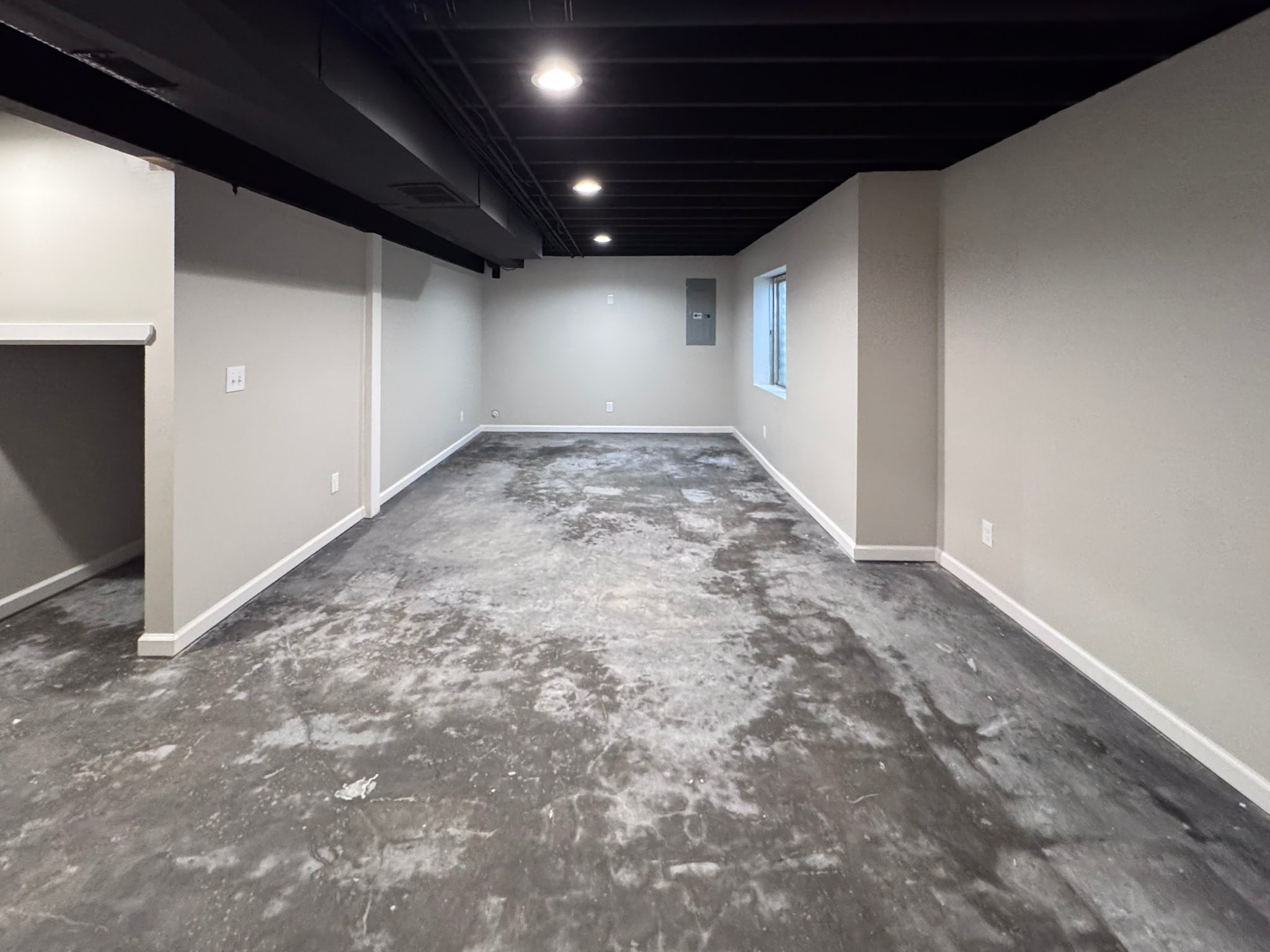 Basement living area nearing completion with finished walls and painted ceiling