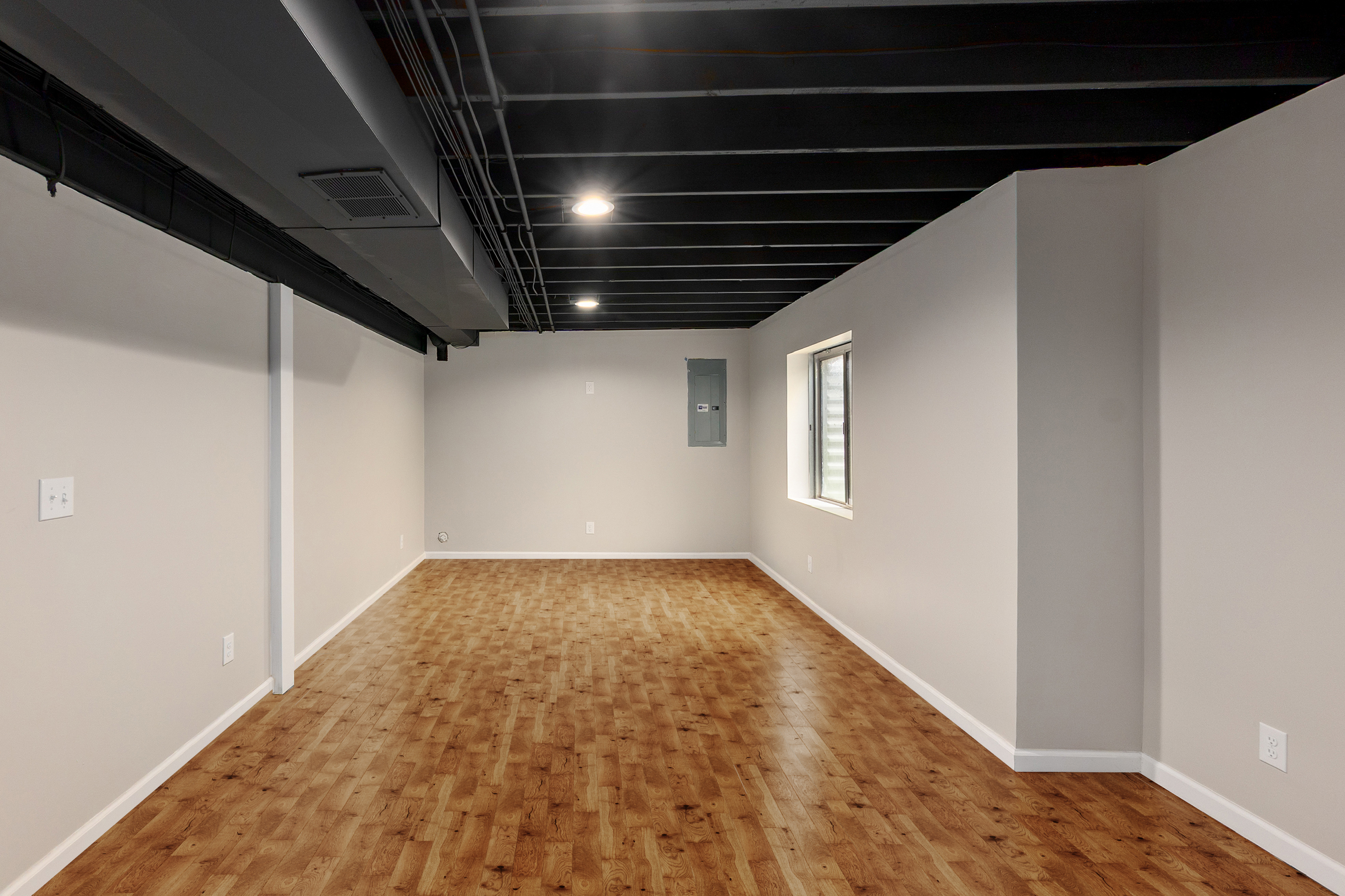 Finished basement living area with wood flooring and window